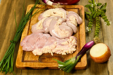 Cow bowels presented on a wooden board with ingredients, ready to grill