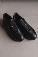 Close up details of black sneakers on the floor. Casual fashion style minimalistic shoes.
