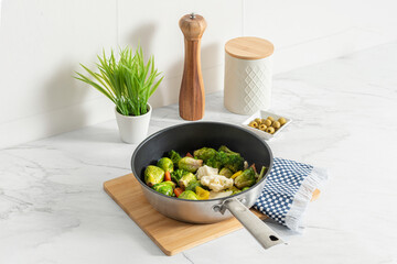 a pan containing an array of colorful healthy vegetables on a modern white marble kitchen...
