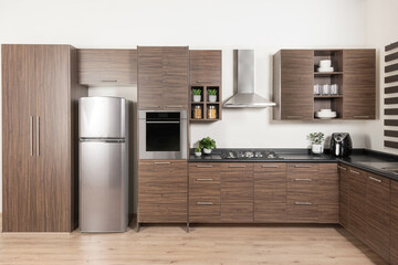a modern design Modular Kitchen cabinet, stainless steel refrigerator with drawers and brown melamine cabinets - obrazy, fototapety, plakaty