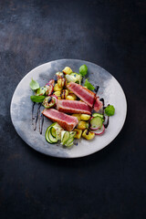 Traditional Italian fried tuna fish steak with gnocchi and cucumber slices served as close-up on a Nordic design plate