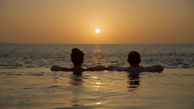Couple entering private pool at sunset and kissing