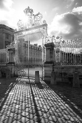 Golden entrance gate to the courtyard of Chateau Versailles near Paris, France. Black and white...