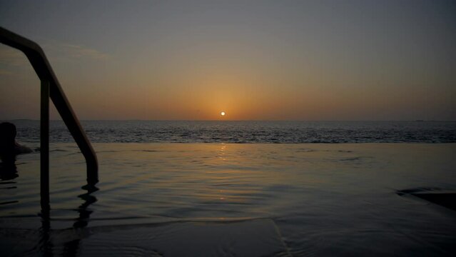 Couple playing in pool at sunset