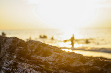 Blurry background of people playing at the beach in sunset time