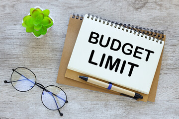 wooden table. open notebook with text budget limit