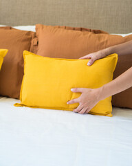 Mujer acomodando almohadones en la cama de la habitación