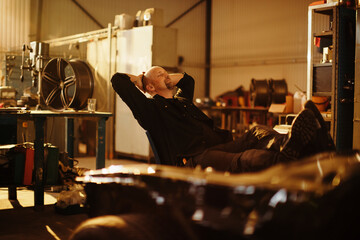 Male car mechanic taking a break form working in a mechanics shop