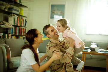 Father reuniting with his wife and daughter at home after deployment