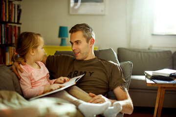 Father reading a story to his daughter while still in his military uniform