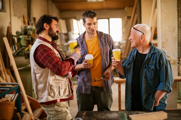 Multigenerational group of carpenters having a coffee break at the carpenters shop