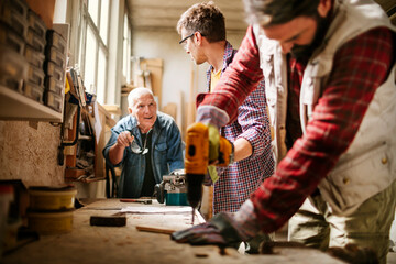 Multigenerational group of carpenters working together in a woodworking workshop