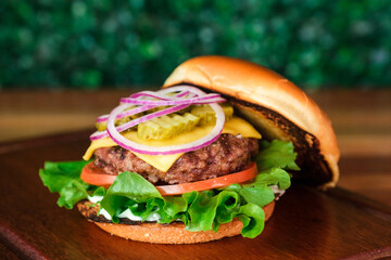 Hambúrguer aberto delicioso no fundo verde desfocado e bancada de madeira