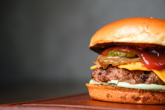 Hamb&uacute;rguer delicioso no fundo escuro e bancada de madeira