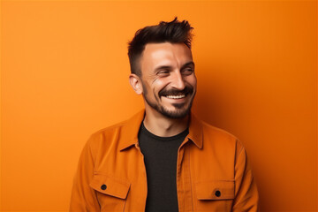 Fototapeta premium Caucasian young adult man smiling on a orange background