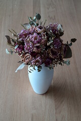 Dried bohemian bridal boquet in a white vase on an oakwood table