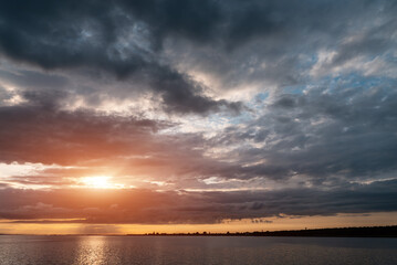 beautiful sunset over sea with dramatic clouds and orange sun light