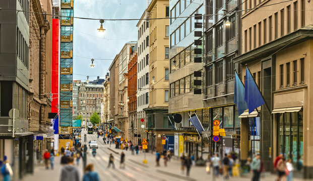Street of Helsinki, commercial buildings at evening with lots of pedestrians and tourists walking around and looking sights. Nice street lighting. Good detailed tourism photo