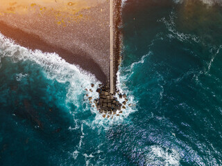 ocean blue water waves and stone breakwater with black beach, Tenerife, Canary