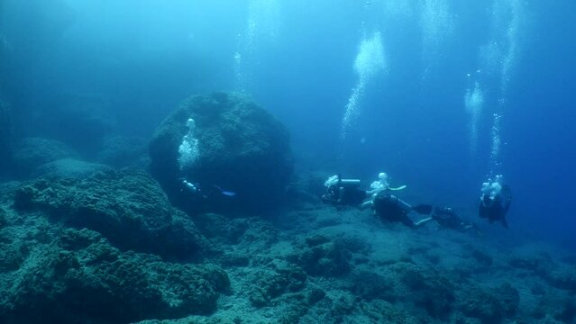 scuba divers explorig the reefs ad rocks enjoying the topography underwater