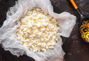 Fresh cottage cheese on gauze on a black background