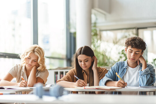 Group Of Smart Pensive School Girls And Boy Studying Together, Learning Language, Writing, Exam Preparation In Modern Classroom. Back To School, Education Concept