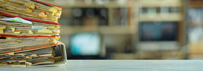 stack of dusty messy file folders with narrow depth of field, blurred office in the back,red tape,...