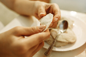 Obraz na płótnie Canvas A woman in the kitchen is making dumplings from stuffed dough.