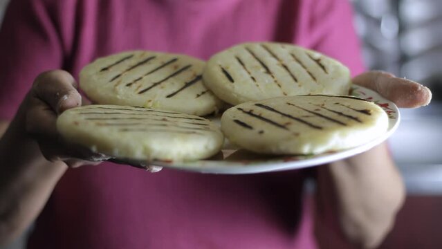 woman presents some delicious Colombian arepas in a kitchen
