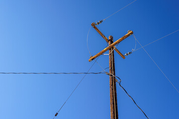Wooden electrical pole with wires and clear blue sky