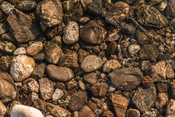 Sea stones in the sea water. Pebbles under water. The view from the top. Nautical background. Clean sea water. Transparent sea.