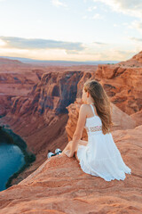 Fototapeta na wymiar Happy girl on the edge of the cliff at Horseshoe Band Canyon in Page, Arizona. Adventure and tourism concept. Beautiful nature in USA