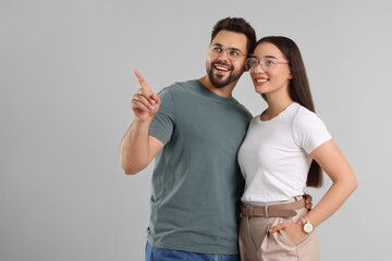 Beautiful couple wearing glasses on light gray background, space for text