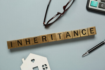 Word Inheritance made with cubes, house model and pen on light blue background, flat lay