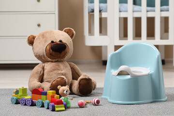 Light blue baby potty and toys on carpet in room. Toilet training