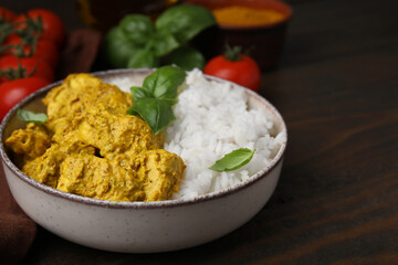 Delicious rice and chicken with curry sauce on wooden table, closeup