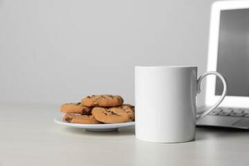 One ceramic mug, laptop and tasty biscuits on white table