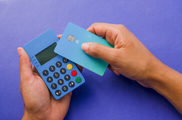 Hands holding a portable contactless payment device, An ultra-light and modern credit card next to...