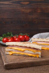 Delicious grilled sandwiches with ham and cheese on wooden table