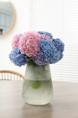 Vase with beautiful hydrangea flowers on wooden table indoors