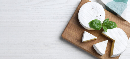 Tasty brie cheese on white wooden table, top view. Banner design with space for text