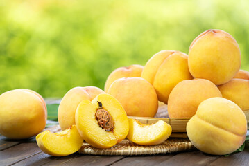 Naklejka na ściany i meble Yellow Peach fruit on wooden basket in garden background, Fresh Yellow Peach.