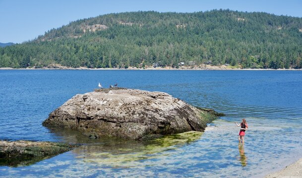 Girl explores the rocky shore of Russell Island, Gulf Islands, British Columbia, Canada 