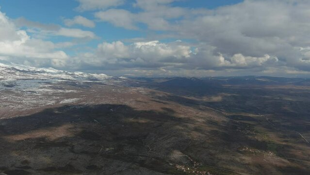 Aerial of Bosnian Dinaric Mountain Range and Villages Beneath It Under the Sky 4K