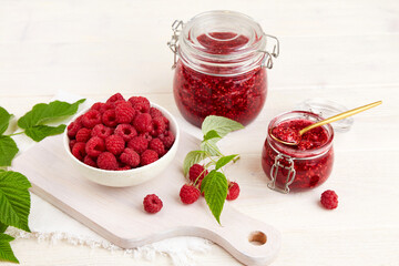Jars of raspberry jam and a bowl of fresh berries. Homemade jam.