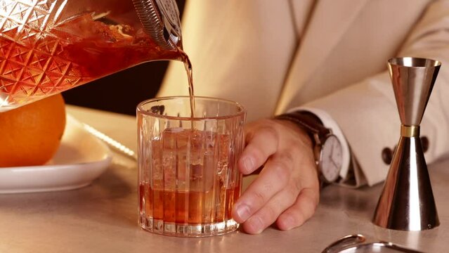 Bartender pouring a Negroni cocktail into a glass