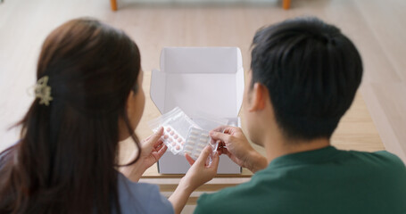 Young married asia people prepare pregnant plan preconception drug at home sofa. Health care unbox open Rx mail parcel covid first aid kit box self cure buy pill order online by clinic service store.