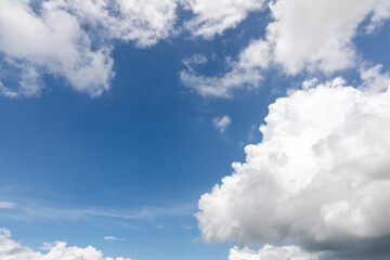 A horizontal shot of bright blue sky with puffy white clouds.