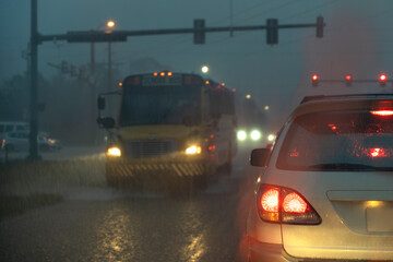 Cars waiting at traffic light at night during rain falling on american wide multilane street...
