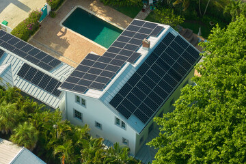 Expensive american residential house with rooftop covered with solar photovoltaic panels for producing of clean ecological electrical energy in suburban rural area. Concept of autonomous home